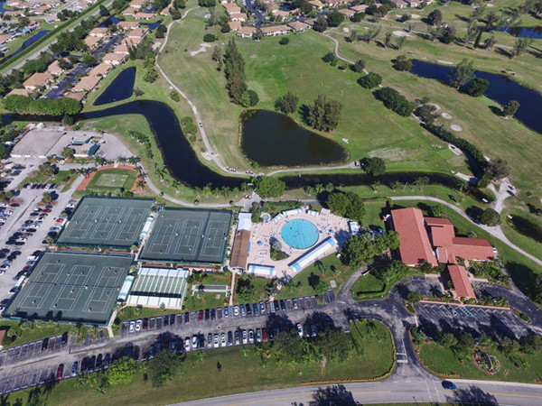 View of Palm Greens Clubhouse, main pool, tennis courts, shuffleboard & bocci.